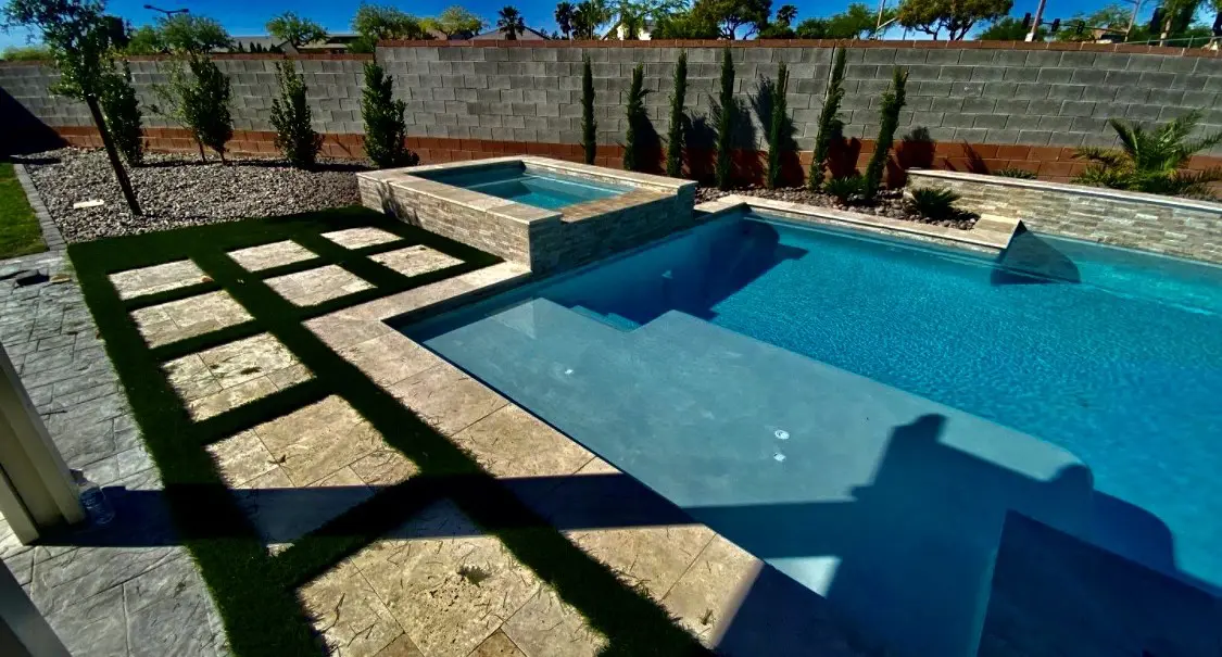 A pool with a stone wall and a bench